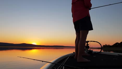 Bass-fishing-on-a-beautiful-calm-lake-with-the-sun-setting-in-the-distance