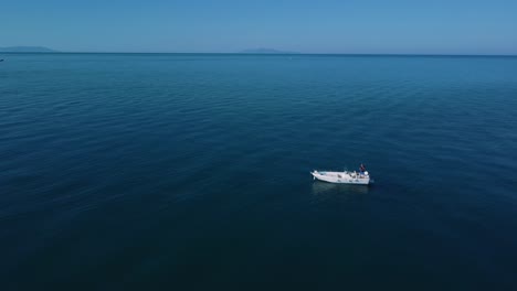Drone-flying-over-fishing-boat-in-Tuscany,-Italy-at-a-sandy-beach-at-the-seaside-near-Alberese-in-the-iconic-Maremma-nature-park-by-sunset