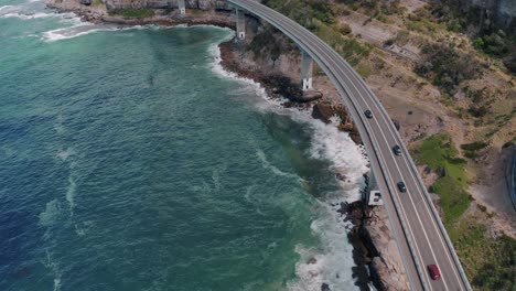 Fahrzeuge,-Die-An-Der-Seeklippenbrücke-Mit-Krachenden-Wellen-In-New-South-Wales,-Australien,-Fahren