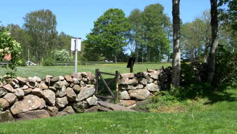 Stone-wall-in-the-countryside-on-a-beautiful-day,-Sweden,-wide-shot-pan-right