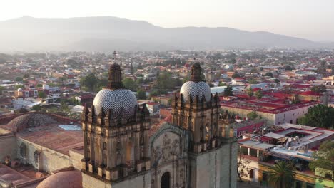 Aerial-View,-Domes,-Towers-and-Facade-of-Santo-Domingo-de-Guzman-Church,-Oaxaca-City-Mexico,-Landmark-of-Historic-Colonial-Downtown,-Parallax-Drone-Shot
