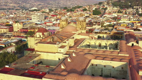 Oaxaca-Historic-Downtown,-Aerial-View-of-Santo-Domingo-De-Guzman-Catholic-Church-and-Neighborhood,-Unesco-World-Heritage-SIte-on-Golden-Hour-Sunlight,-Revealing-Drone-Shot