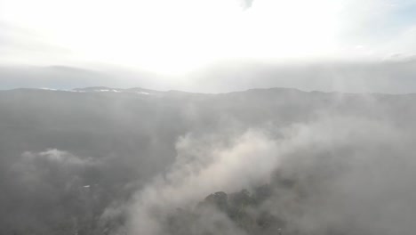 Crossing-over-mist-above-the-mountains-forest-at-sunrise-with-a-drone
