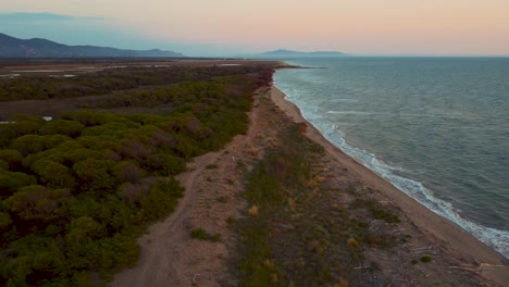 Cinematic-high-altitude-aerial-drone-footage-above-a-sandy-sunset-beach-at-the-seaside-near-Alberese-in-the-iconic-Maremma-nature-park-in-Tuscany,-Italy,-with-waves,-islands-and-a-dramatic-red-sky