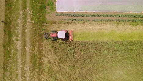 Tractor-With-Mower-Cutting-The-Grass-Of-A-Field---aerial-top-down