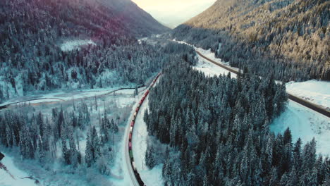 Langer-Industriezug,-Der-Im-Winter-Am-Schneebedeckten-Wald-Im-Glacier-National-Park-Vorbeifährt