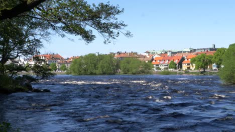 Strong-currents-under-a-blue-sky,-River-Atram-in-Falkenberg,-Sweden,-wide-shot