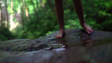 Woman's-feet-seen-stepping-into-a-shallow-stream-in-the-forest---slow-motion