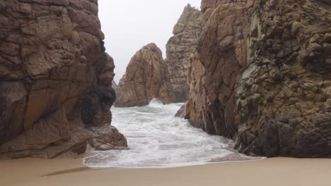 Waves-coming-in-through-a-Rocky-Outcrop-in-Praia-da-Ursa,-Portugal