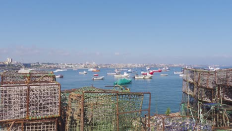 Panning-Shot-of-Traditional-Fishing-Cages-and-Boats-Mooring-in-the-background-by-the-Cascais-Marina,-Portugal