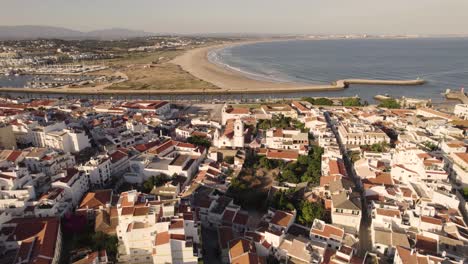 Backwards-aerial-of-the-old-town-of-Lagos-in-Portugal-with-the-ocean-in-the-background