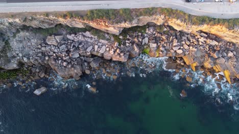 AERIAL-Top-Down-Panning-Shot-of-a-Rocky-Coastline-in-Cascais,-Portugal