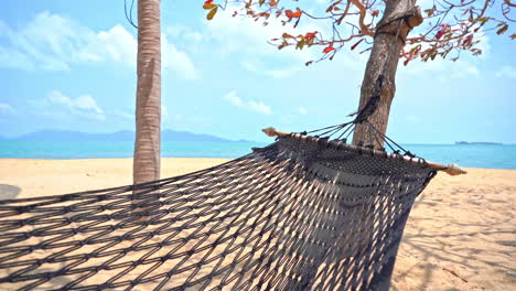 Empty-rope-hammock-hanging-between-trees-on-sandy-tropical-island-beach-on-a-sunny-cloudy-day-in-the-Philippines