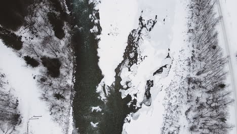 Vista-De-Arriba-Hacia-Abajo-Del-Río-Congelado-Durante-El-Invierno-En-Trollstigen,-Noruega---Toma-Aérea