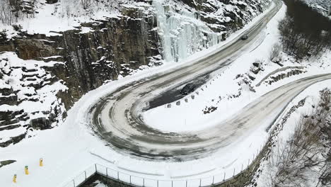 Car-Driving-In-The-Road-By-The-Snowy-Mountains-In-Geirangerfjord-Norway---aerial-shot