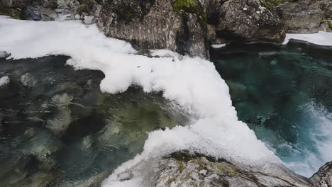 Blick-Auf-Einen-Zugefrorenen-Fluss-Und-Einen-Kleinen-Wasserfall-In-Norwegen---Schwenk-Nach-Rechts