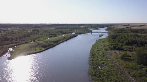 Traffic-on-country-bridge-over-prairie-river-valley,-aerial-view