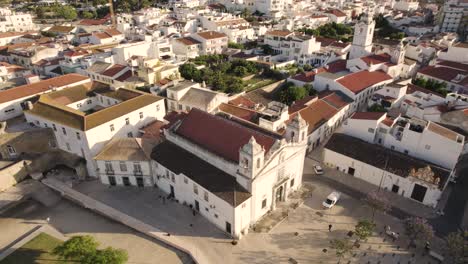 Aerial-of-Igreja-de-Santo-António,-an-ornate-18th-century-church-that-sits-across-from-the-Castelo-dos-Governadores,-a-castle-with-a-baroque-facade-and-watchtowers-in-Lagos-Portugal
