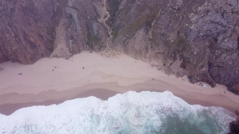 AERIAL-Rotating-Shot-of-a-Moody,-Wild-Beach-at-Praia-da-Ursa,-Portugal