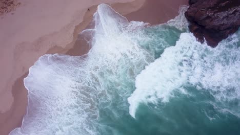 AERIAL-Fast-Top-Down-Rotating-Shot-of-Wild-Waves-at-Praia-da-Ursa,-Portugal