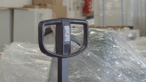 Warehouse-worker-reaches-into-frame-to-pull-hand-truck-handle,-close