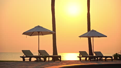 Sonnenschirme-Und-Liegestühle-Leer-Am-Sandstrand-Von-Thailand-Mit-Meer-Im-Hintergrund-Bei-Sonnenuntergang