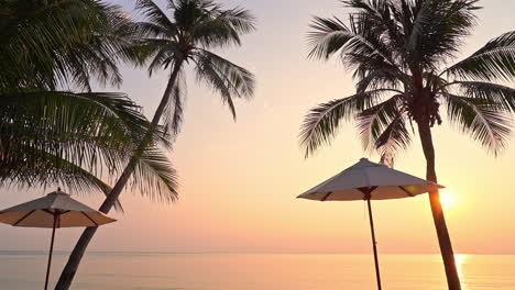 Tropische-Inselküste-Bei-Sonnenuntergang,-Palmen-Und-Sonnenschirmsilhouette-In-Strandnähe