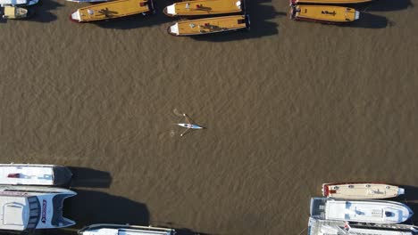 Aerial-top-down-shot-of-rowing-canoe-on-brown-River-in-Tigre-during-sunny-day