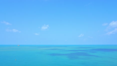 Cielo-Azul-Y-Mar-Tropical-Turquesa-Con-Bote-Pequeño-En-El-Horizonte-En-Un-Día-Soleado-De-Verano,-Cuadro-Completo