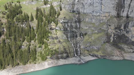 Pull-out-aerial-away-from-multiple-waterfalls-crashing-into-the-Oeschinesee-in-Switzerland
