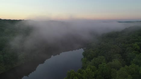 Beautiful-forest-river-with-rising-fog-in-early-summer-morning,-aerial-view