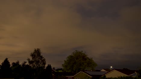 Sunrise-Time-lapse-of-fast-moving-clouds-and-stars-on-windy-day-above-suburban-rooftops-and-tree-tops-in-the-UK