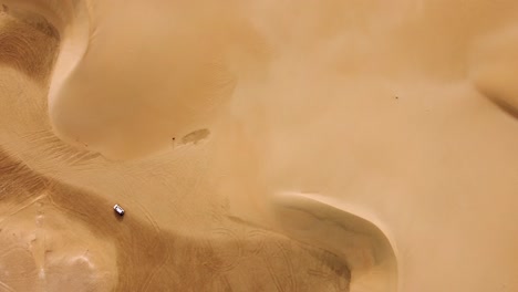 Lonely-white-car-on-top-of-desert-dune-in-top-down-descend-aerial-view