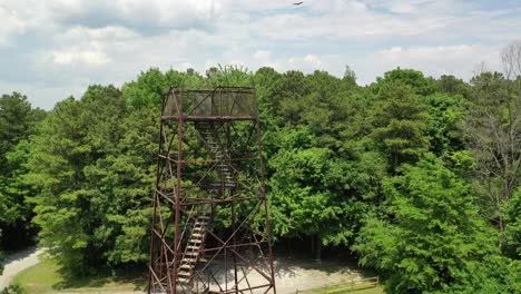 Landscape-viewing-tower-surrounded-by-lush-and-dense-forest,-drone-orbit-view