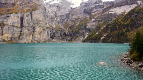 Aufsteigende-Luftaufnahme-Der-Berge-Am-Türkisfarbenen-Gletschersee-Oeschinensee