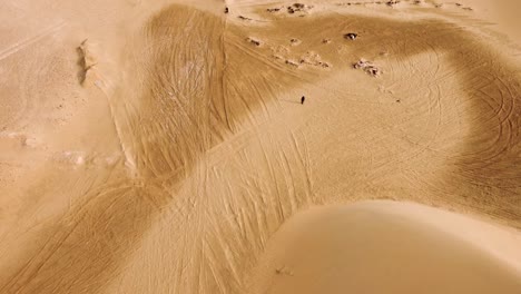 Lonely-nomad-walking-through-deadly-hot-desert-in-aerial-view