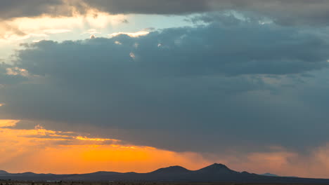 Colorful-and-dynamic-cloudscape-with-a-cloudburst-over-a-mountain-range-in-silhouette-at-sunrise---static-time-lapse