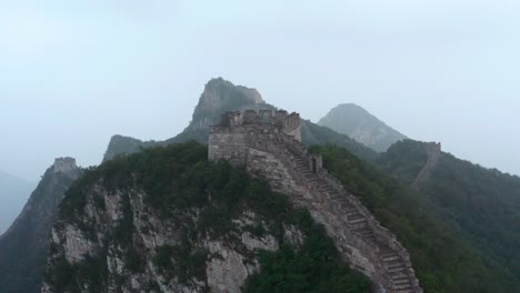 Fliegen-Sie-An-Einem-Bewölkten-Tag-über-Den-Alten-Teil-Der-Chinesischen-Mauer-Mit-Einem-Verfallenen-Aussichtsturm-Auf-Dem-Gipfel-Des-Berges