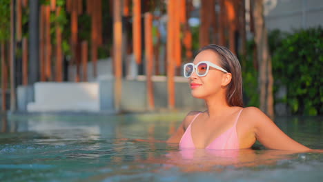 Rich-exotic-woman-in-bikini-and-sunglasses-enjoying-in-jacuzzi-pool-on-tropical-holiday,-full-frame-slow-motion