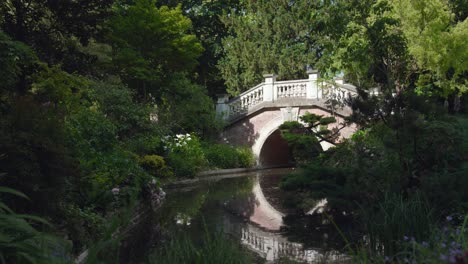 Static-view-of-Parc-Monceau-with-beautiful-stone-bride-across-river-on-summer-day-in-Paris,-France
