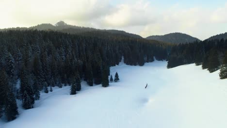 Aerial-drone-shot-of-white-mountains-and-hiker-hiking-uphill-the-snow-landscape-in-France