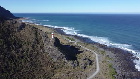Flying-towards-a-lighthouse,-high-on-a-cliff-in-Cape-Palliser,-New-Zealand