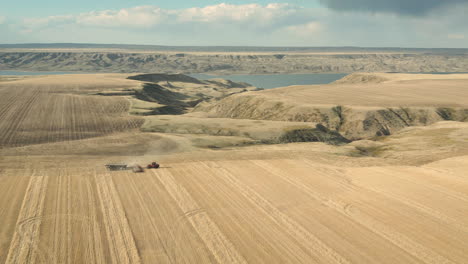 Volando-Hacia-La-Maquinaria-Del-Tractor-Plantando-Semillas-En-El-Suelo-Polvoriento-En-Saskatchewan,-Canadá