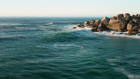 Antena-De-La-Playa-De-Lladudno-Donde-Los-Surfistas-Se-Relajan-En-El-Agua-En-Ciudad-Del-Cabo,-Sudáfrica