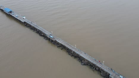 Drone-flying-along-the-length-of-pier-extending-from-land-out-over-into-the-sea