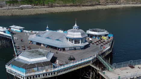 Llandudno-pier-seaside-resort-landmark-silver-pavilion-wooden-boardwalk-aerial-view-zoom-in