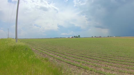 Slow-pan-of-a-field-with-large-looming-storm-clouds-in-the-distance