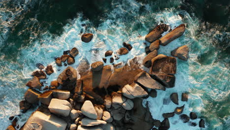 Waves-crashing-on-a-group-of-rocks-with-sunset-in-Llandudno,-Cape-Town,-South-Africa