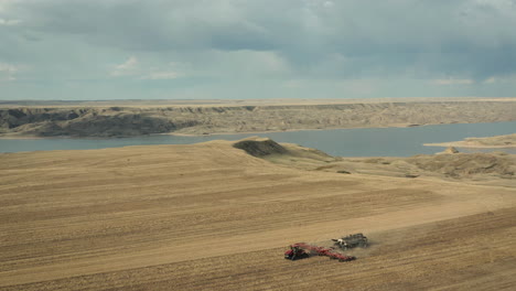 Seeder-Machinery-Working-On-Farmland-With-Scenic-River-breaks-As-Backdrop-In-Saskatchewan,-Canada