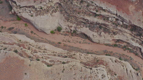 Drone-Over-Rocks-And-Riverbeds-In-Utah,-Tilt-up-Revealing-Road---aerial-shot